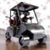 Une figurine en métal représentant une voiturette de golf avec 2 golfeurs