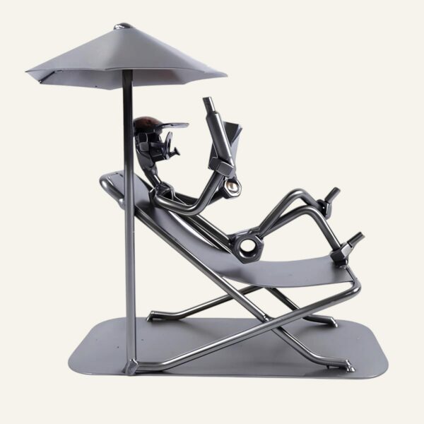 Figurine en métal artisanale représentant un homme en train de lire sous un parasol sur un transat, idéale comme idée de cadeau ou déco retraite pour homme