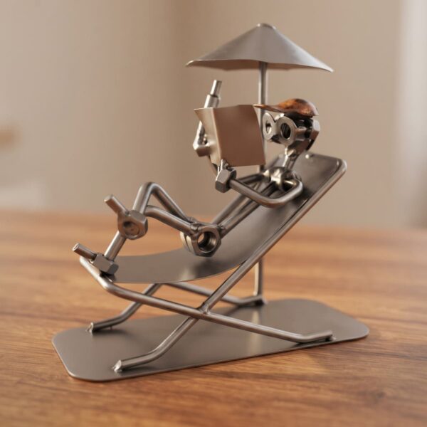 Figurine en métal artisanale représentant un homme en train de lire sous un parasol sur un transat, idéale comme idée de cadeau ou déco retraite pour homme